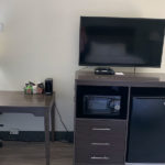 in-room work desk next to TV, microwave, and mini fridge